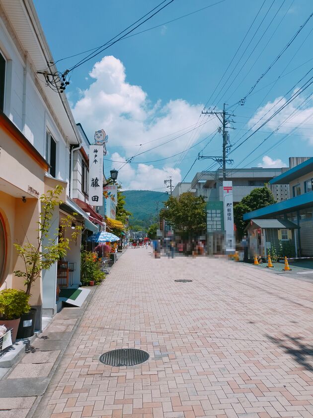 旧軽井沢銀座の通り。歩道の両側に店が並び、奥に山が見える