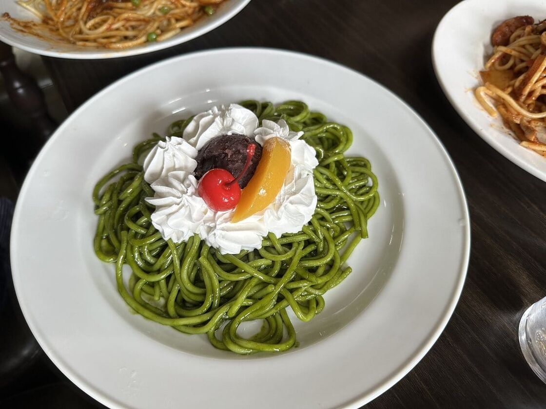 甘口抹茶小倉スパ。緑色の麺の上に小倉あんとクリームが乗っている