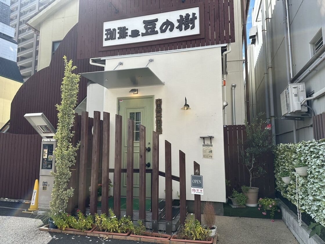 「珈琲 豆の樹」の看板が掛かった白い建物