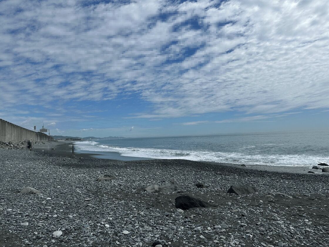 丸い石が敷き詰められた浜と、空に広がるうろこ雲