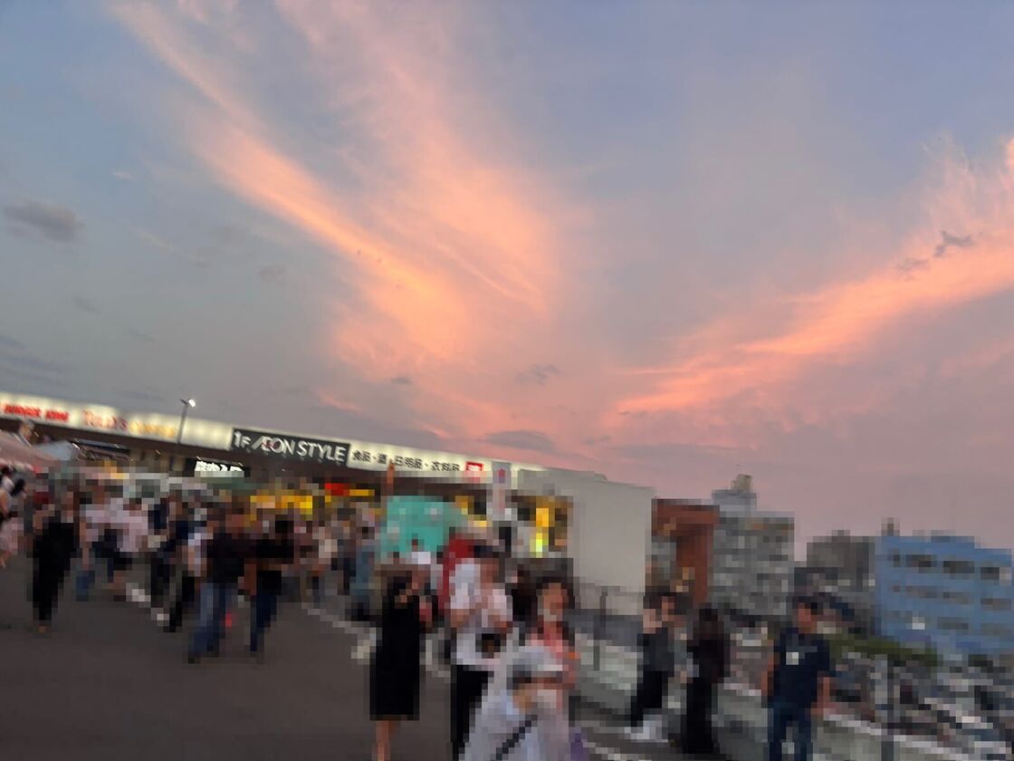 夕焼け空とイオンスタイルの看板、その前を歩く人たち